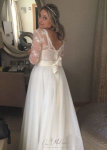 bride wearing lace bridal top and looking in mirror